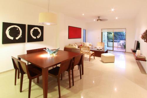 a living room with a dining room table and a couch at Palmar del Sol by Riviera Maya Suites in Playa del Carmen