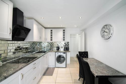 a kitchen with white cabinets and a washer and dryer at Modern Retreat - 3 Beds - Parking - Wifi - 15 mins to tube in London