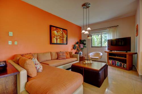 a living room with a couch and a tv at Palmar del Sol by Riviera Maya Suites in Playa del Carmen