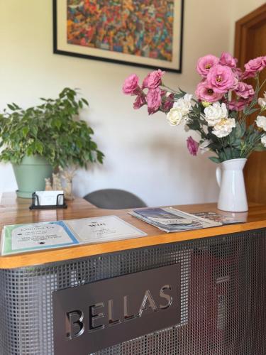 a desk with a television and flowers on it at Bellas apartmani in Novi Sad