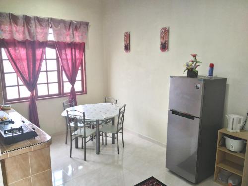 a kitchen with a table and a refrigerator at Z&R HOMESTAY in Kota Bharu