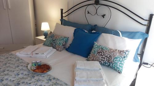 a bed with blue and white pillows and a bowl of food at La Terrazza Solarium, in pieno centro 60m dalla stazione ferroviaria 700m dal mare in Santa Flavia