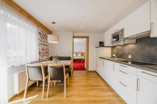 a kitchen with white cabinets and a table with chairs at Pension Gabl in Pfunds