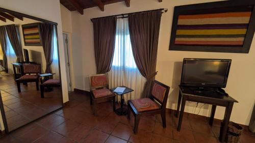a living room with a flat screen tv and chairs at Delvino Boutique Hotel in Salta