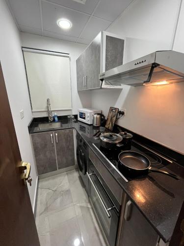 a small kitchen with a stove and a microwave at New Apartment Located in Middle of Bahrain in Manama