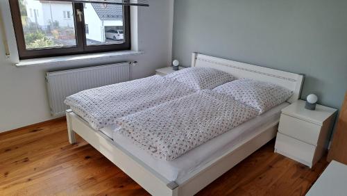 een wit bed in een slaapkamer met een raam bij Wohnung Brand in Neumarkt in der Oberpfalz