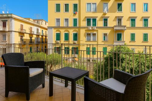 a balcony with chairs and a table and a building at Nella's Carlo III Apartment in Naples