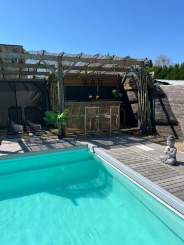 a swimming pool in a yard with a wooden deck at Logement cosy avec piscine et jacuzzi privatifs in Saint-Dolay