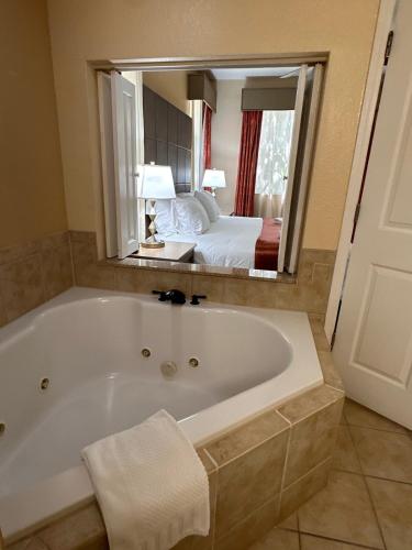a bathroom with a bath tub with a bed in a mirror at Central Location to all Parks and Convention center in Orlando