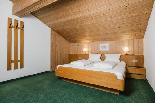 a bedroom with a large bed with a wooden ceiling at Pension Gabl in Pfunds