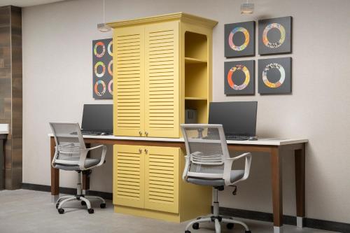 a desk with two chairs and a yellow cabinet at Home2 Suites By Hilton Weston Ft. Lauderdale in Davie