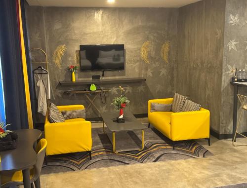 a living room with two yellow chairs and a television at Sri Indar Hotel & Suites in Parit Buntar