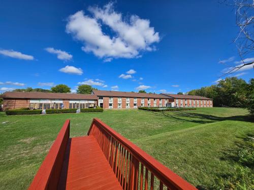 a building with a red fence in front of a field at Fulton Hotel - Oswego Riverfront in Fulton