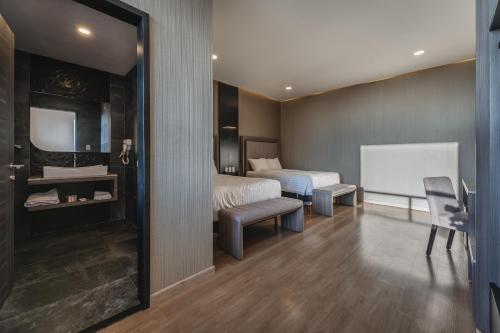 a bedroom with two beds and a desk and a mirror at Hotel Kavia Premium - Paseo Montejo in Mérida