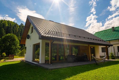 a house with a pitched roof with a patio at Domek na Duzynie in Ochotnica Górna