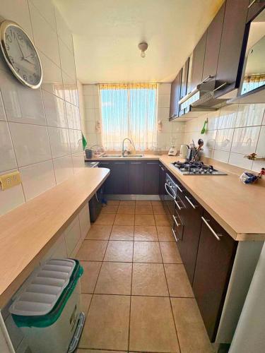 a kitchen with a counter and a clock on the wall at Departamento Costa Manantiales 152 in Concón