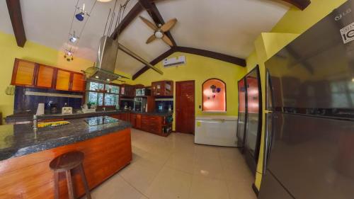 a large kitchen with yellow walls and wooden cabinets at Villa Amable, Lujo entre Selvas y Lagunas in Akumal