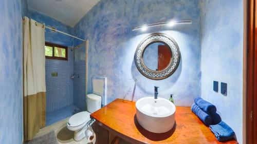 a bathroom with a sink and a toilet and a mirror at Villa Amable, Lujo entre Selvas y Lagunas in Akumal