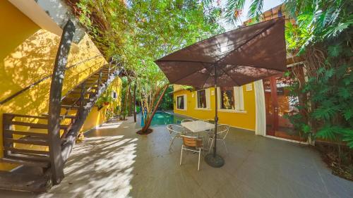 a patio with a table and an umbrella at Villa Amable, Lujo entre Selvas y Lagunas in Akumal