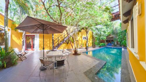 a patio with a table and an umbrella next to a pool at Villa Amable, Lujo entre Selvas y Lagunas in Akumal