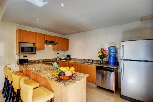 a kitchen with a refrigerator and a counter with a bowl of fruit at Palmar del Sol by Riviera Maya Suites in Playa del Carmen