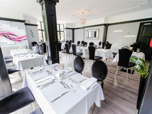 a dining room with white tables and black chairs at Verve Hotel in Bedford