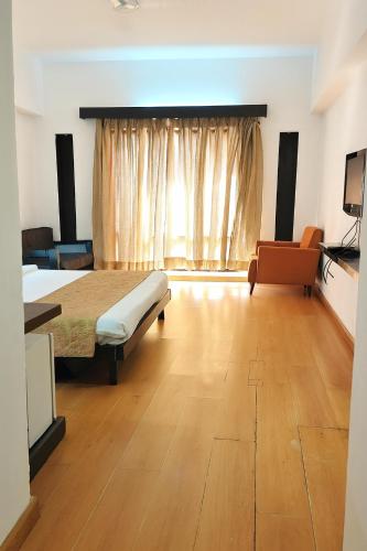 a bedroom with a bed and a couch and a window at The Sky Imperial, Gandhinagar in Gandhinagar