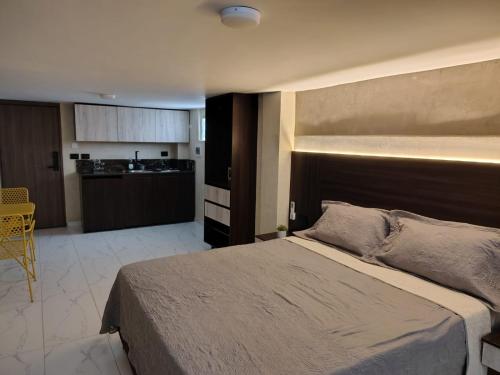 a bedroom with a large bed and a kitchen at Laureles del parque Loft in Barranquilla