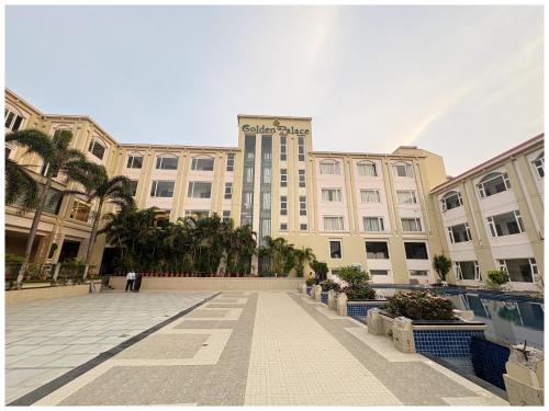 a large building with palm trees in front of it at Private Beach Hotel Golden Palace with Swimming Pool in Puri in Puri