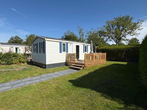a small white cabin with a porch and a yard at Low Budget - Luxe 4 persoons chalet met TV aan het Lauwersmeer in Lauwersoog