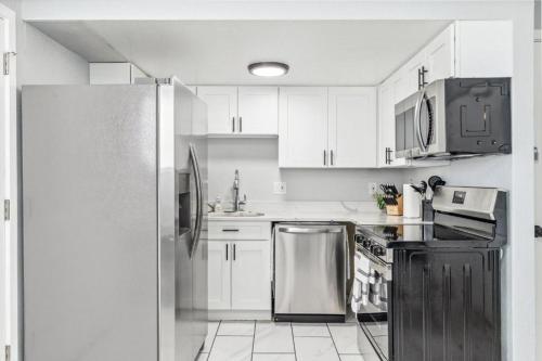 a kitchen with white cabinets and a stainless steel refrigerator at All New! Convenient Location! Sleeps 6 in Denver