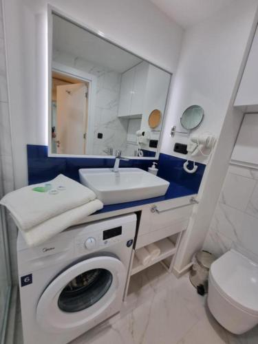a bathroom with a washing machine and a sink at Orbi City Superhost in Batumi