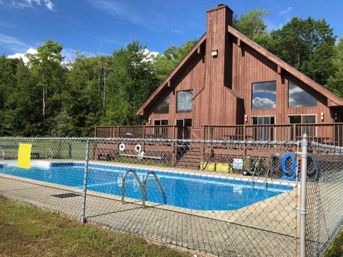 a house with a swimming pool in front of a building at NEWLY REMODELED FOUR BEDROOM All SEASON CONDO W MOUNTAIN VIEWS in East Jewett