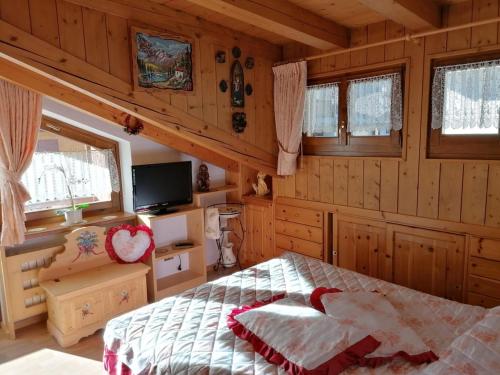 a bedroom with a bed in a room with wooden walls at Stella Alpina Holiday Home in Auronzo di Cadore