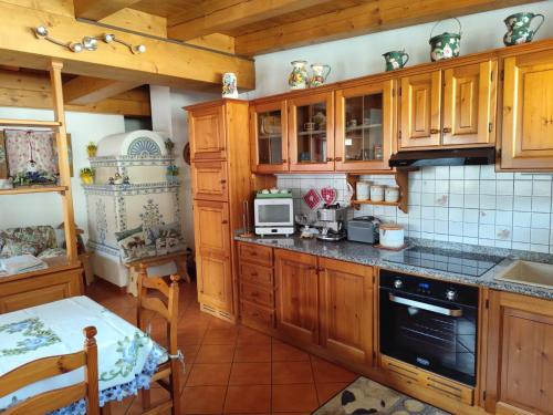a kitchen with wooden cabinets and a table in it at Stella Alpina Holiday Home in Auronzo di Cadore