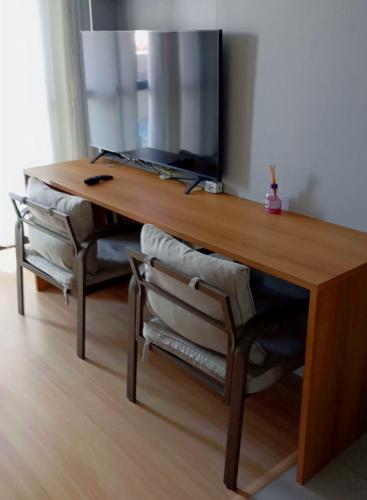 a wooden desk with a television and two chairs at Studio com vista espetacular! in Niterói