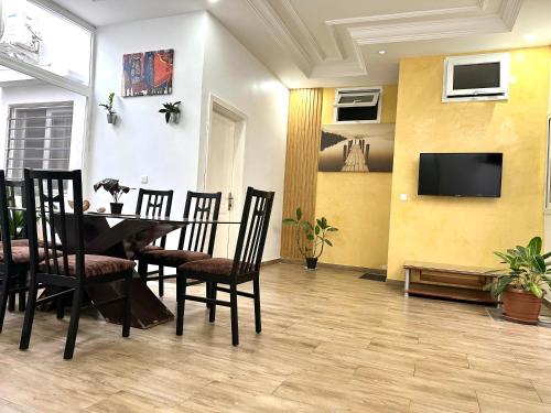 a dining room with a table and chairs and a tv at Belle villa confortable avec gardien in Mbaw Gou Ndaw