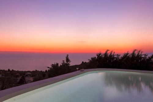 a swimming pool with a sunset in the background at Boo Premium Living Villas in Tsoukaladhes