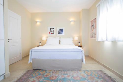 a white bed in a room with a window at Boo Premium Living Villas in Tsoukaladhes