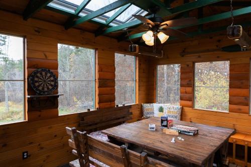 a dining room with a wooden table and windows at Log Home w Mountain Views Near Windham & Hunter Ski Resorts in Maplecrest