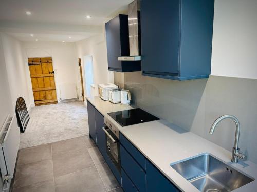 a kitchen with blue cabinets and a sink at River cottage Arundel in Arundel