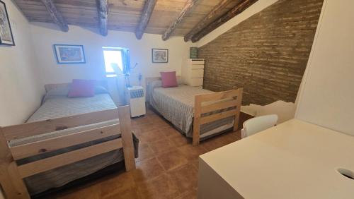 a bedroom with two beds and a brick wall at La Casa de la Iglesia in La Umbría