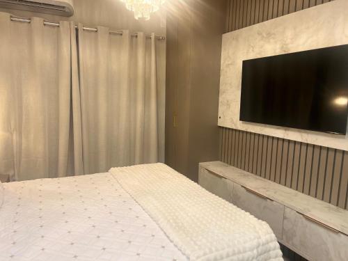 a bedroom with a bed and a flat screen tv at Penthouse with a privileged view in Governador Valadares