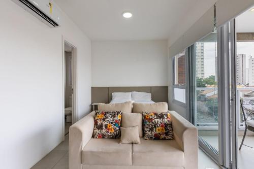 a living room with a couch and a large window at Belo Studio Varandas - Vila Mariana | Delfhy in Sao Paulo
