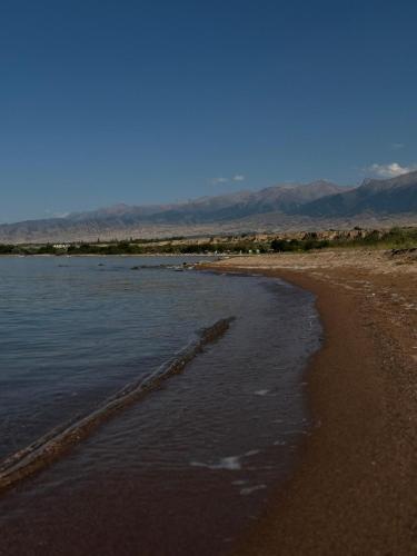 a beach with water and mountains in the background at Home in Tosor, Kyrgyzstan in Tossor