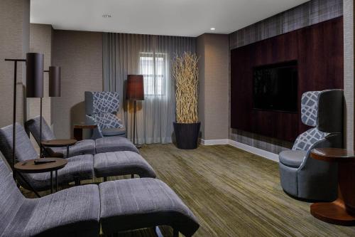 a hotel room with couches and a tv and a living room at Courtyard Long Island MacArthur Airport in Ronkonkoma