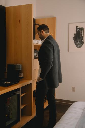 a man standing in front of a cabinet at Tá Hotel de diseño in Querétaro
