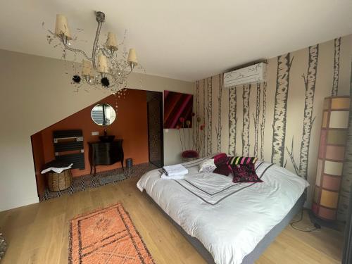 a bedroom with a bed and a chandelier at La suite de Chantepie in LʼIsle-Adam