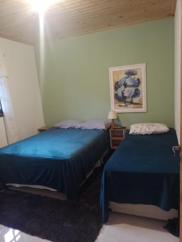 two beds in a room with blue sheets at Sítio Jabuticabeira in Santo Antônio do Pinhal
