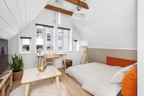 ein Schlafzimmer mit einem Bett und einem Tisch und Fenstern in der Unterkunft Historic Bergen house in the middle of the city center in Bergen